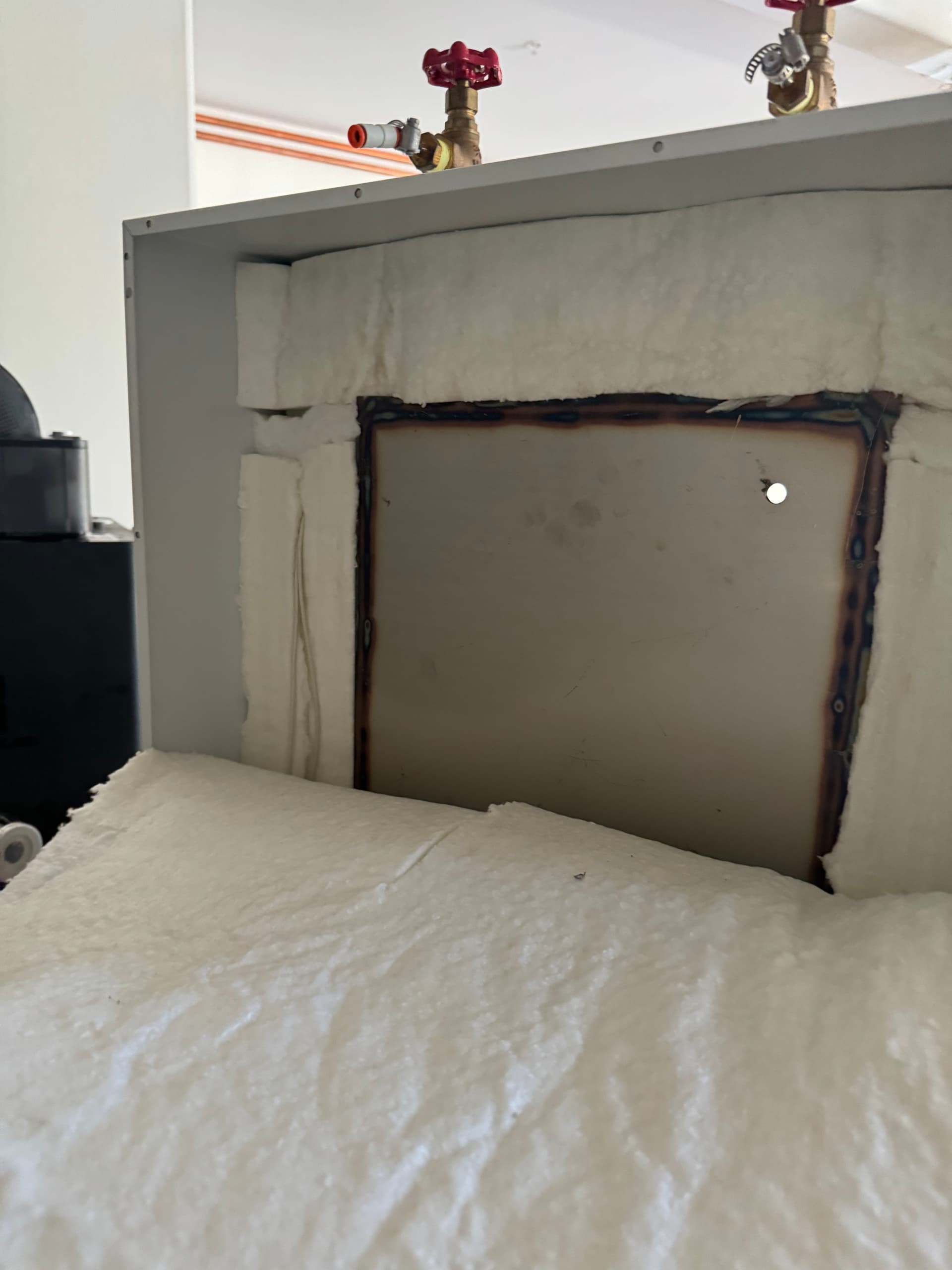 Rear of the oven with the back plate pulled off, exposing the ceramic fiber insulation and steel shell before the fitting was installed.