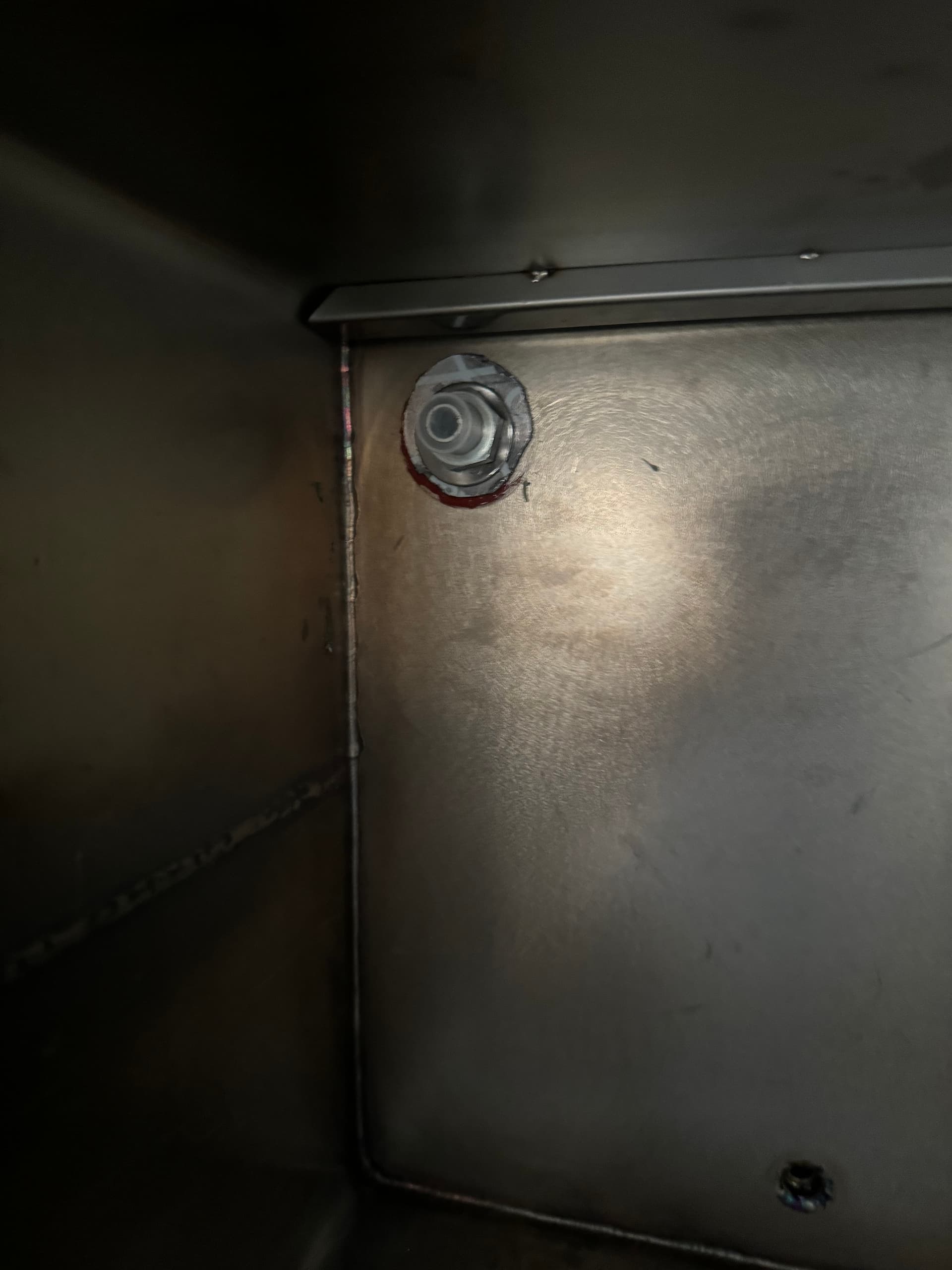 Interior view of the NPT fitting seated in the drilled penetration, sealed against the stainless steel wall with a high temp gasket and sealant.